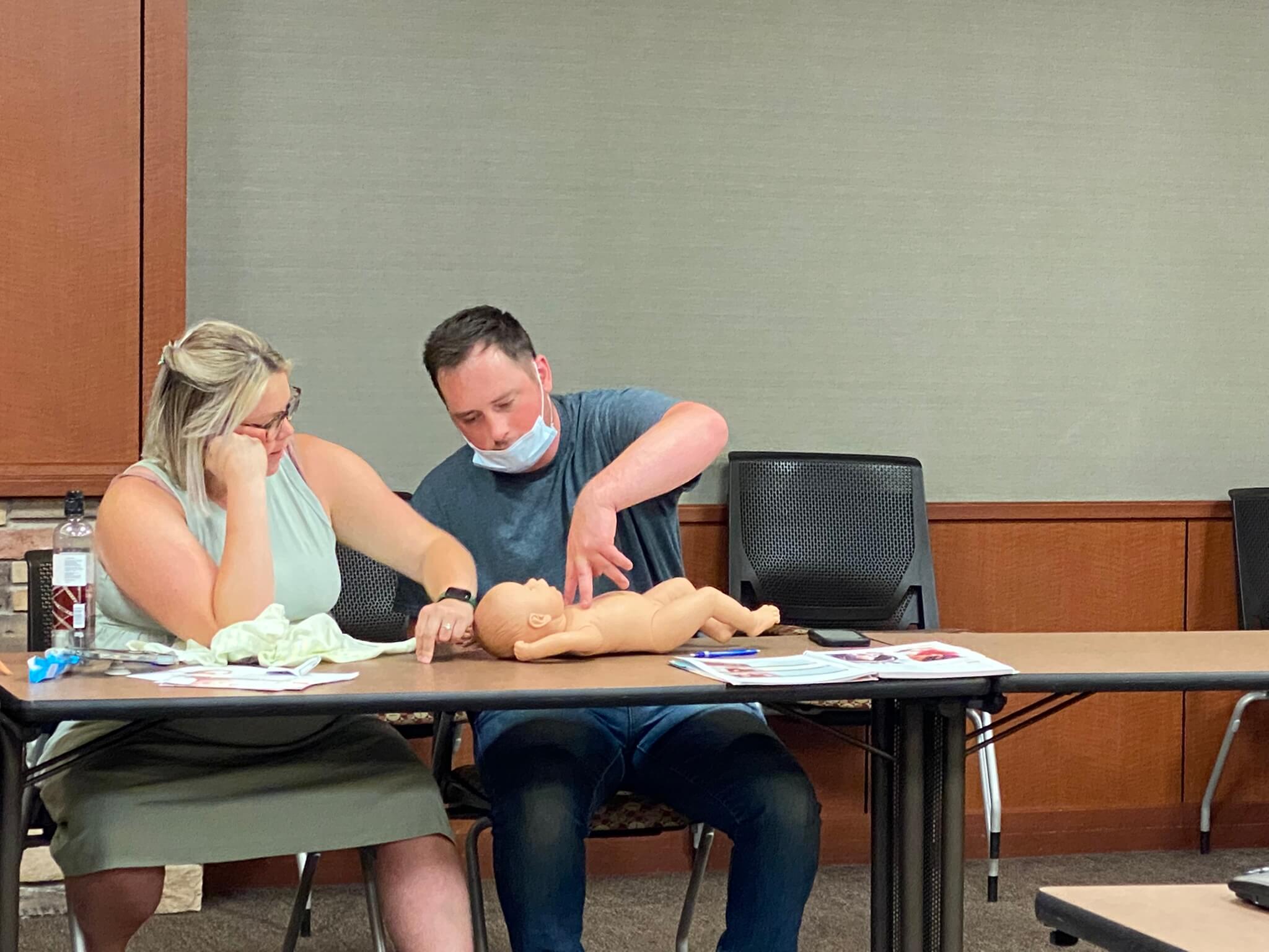 a couple practicing cpr on a fake baby